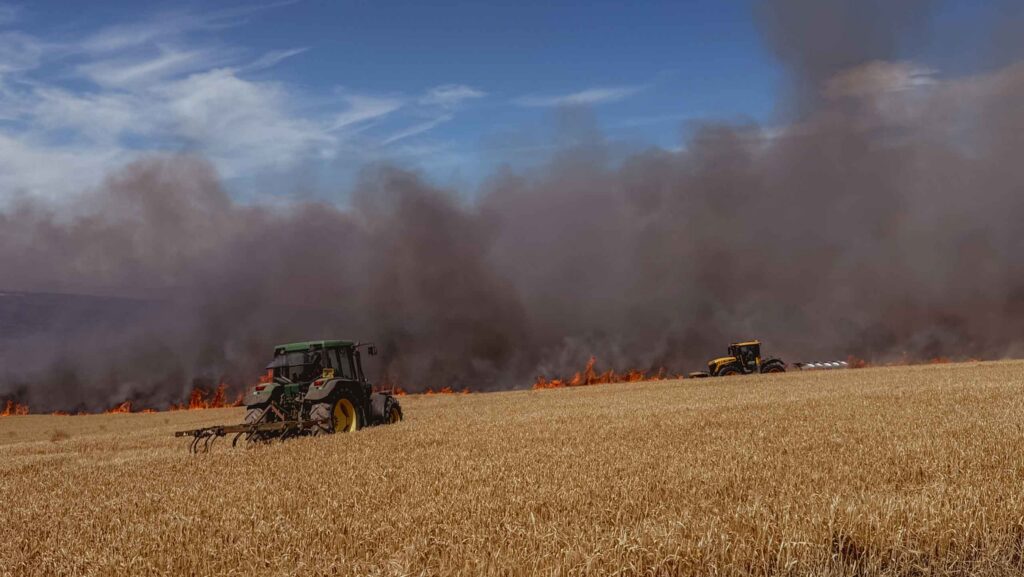 Tractors in field with fire