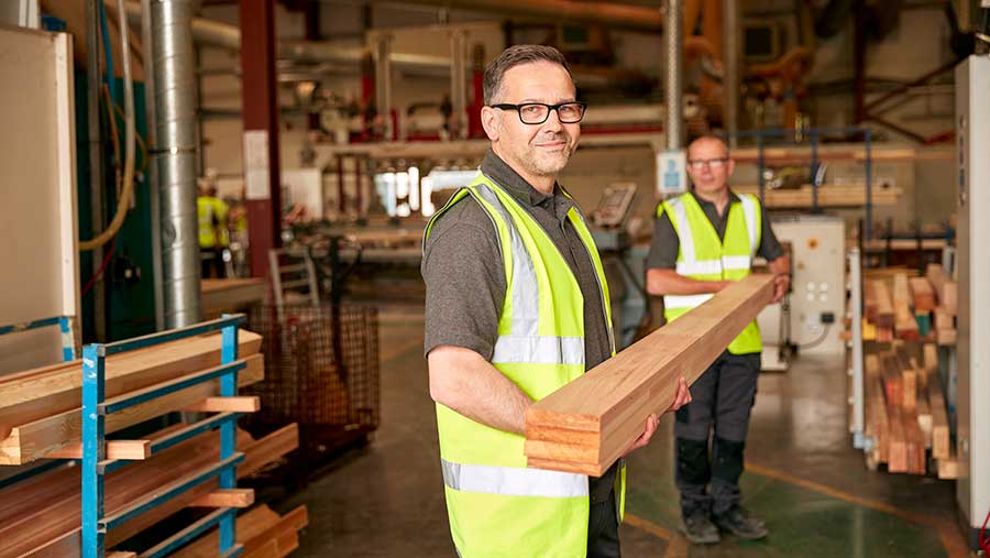 Man with high-vis holding timber