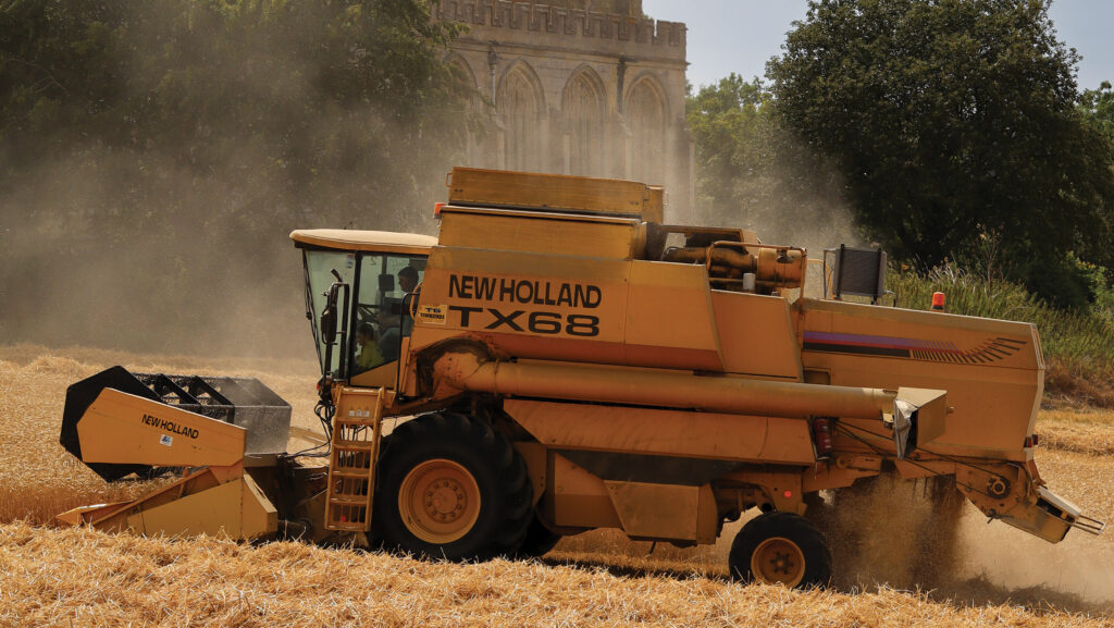A New Holland TX68 cuts a crop of Extase winter wheat against a backdrop of the local church