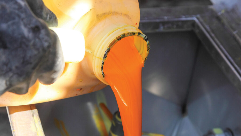 Pouring a can of herbicide into the sprayer induction hopper