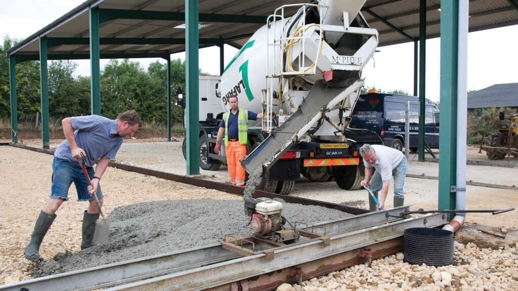 Workmen laying concrete in an agricultural shed