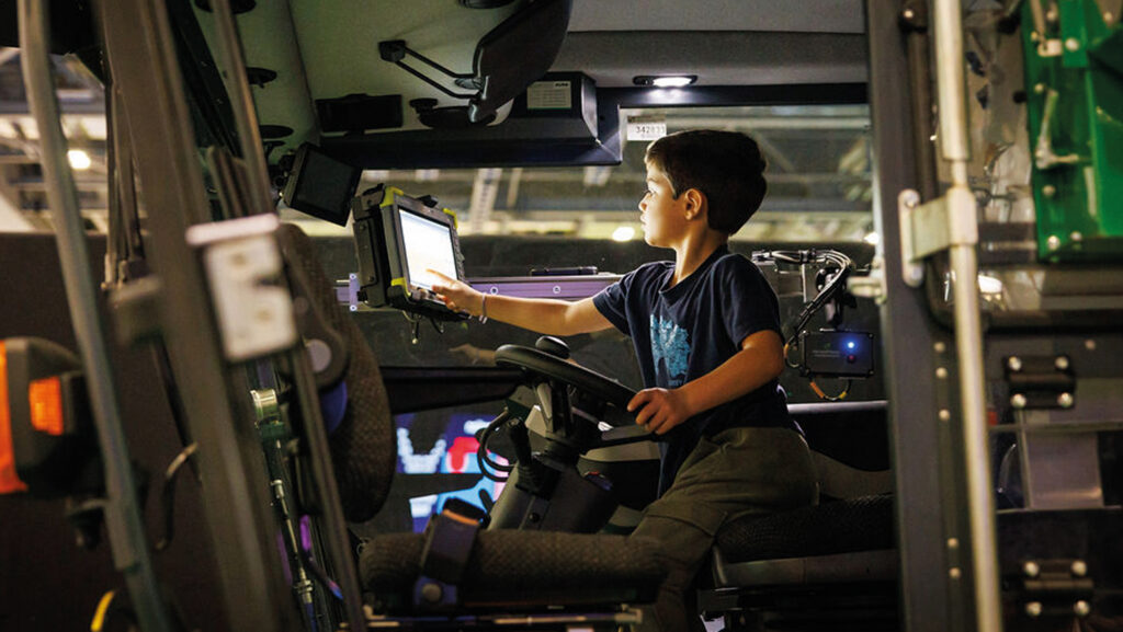 A young boy sits in a tractor cab at New Scientist Live