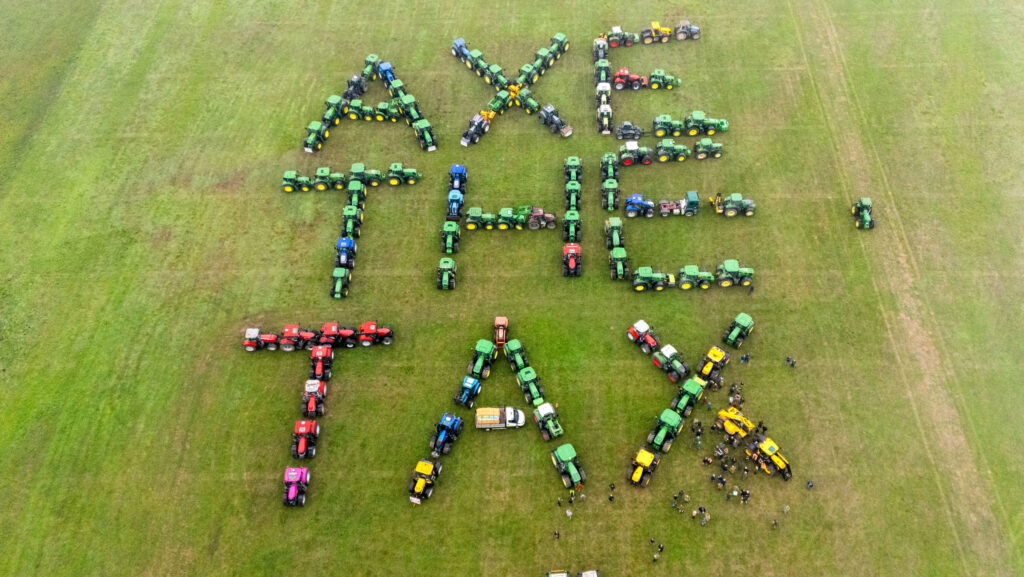 A drone shot of tractors in a field, arranged to spell out "AXE THE TAX"