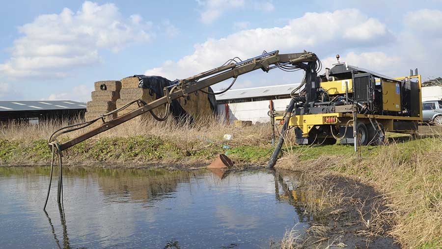 The crane lifts the pump into the lagoon.