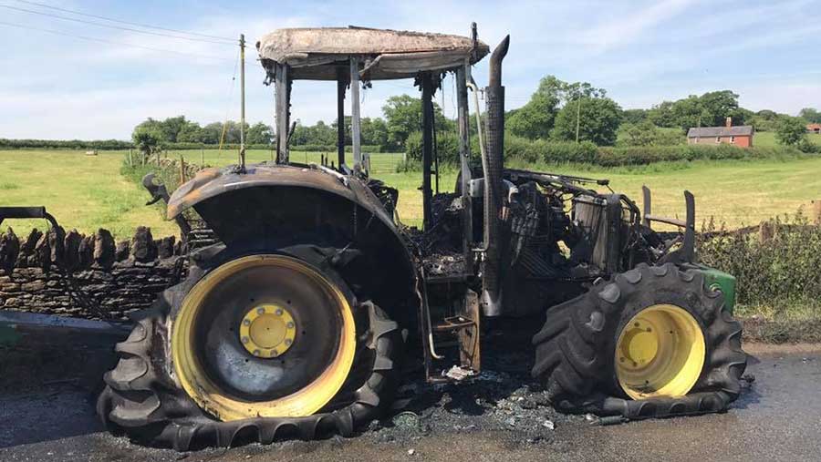 A burned out John Deere tractor stands in the road