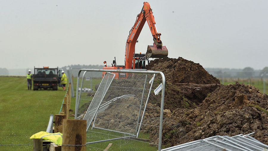 A digger works on a construction project on farmland