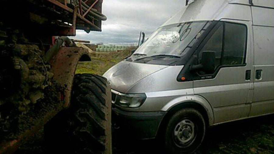 A sprayer is parked next to a van