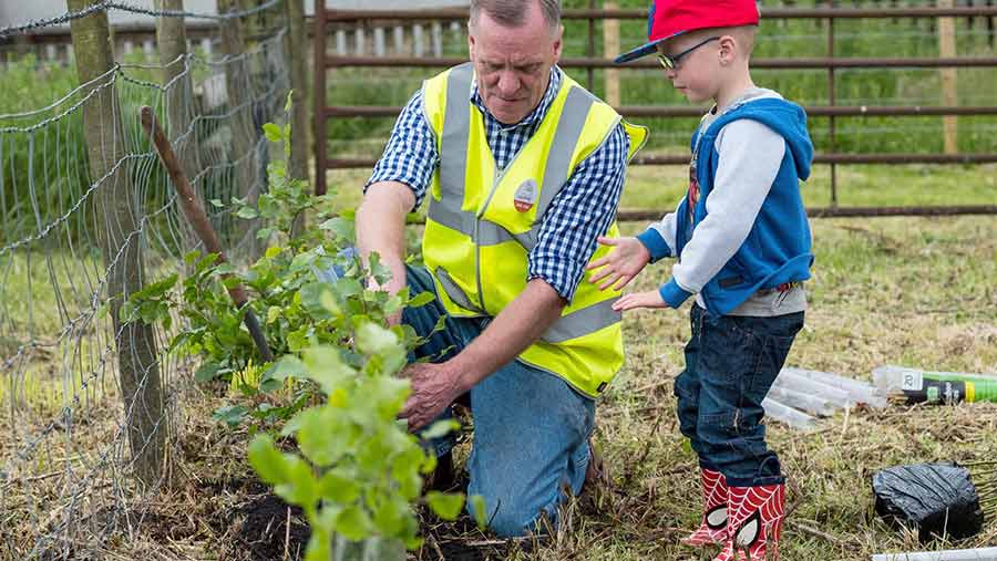 A young boy watches as a man tends to a crop