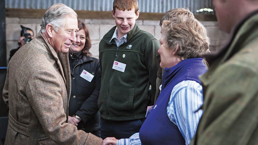 Prince Charles greeting people on a farm