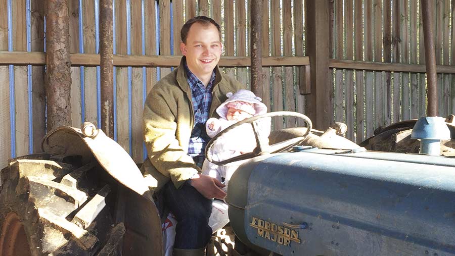 Will Sargent sits on a tractor with his baby daughter Eve in his arms