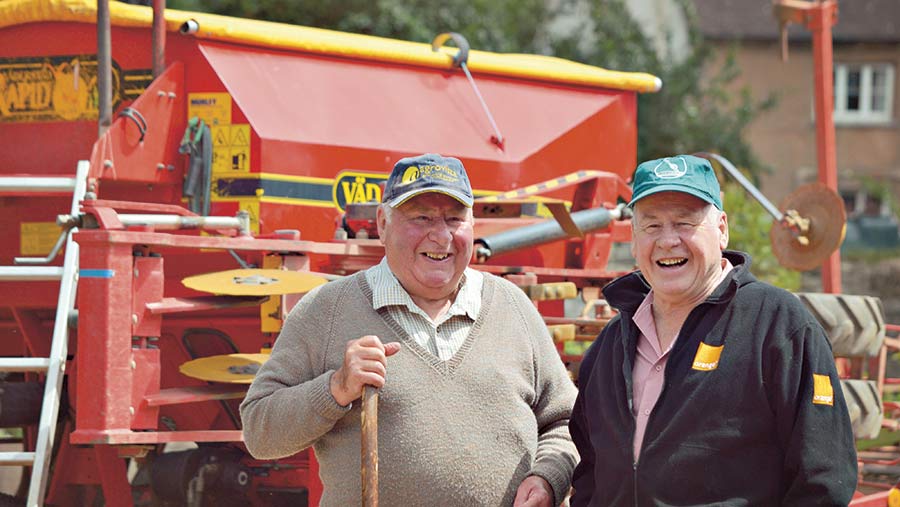 Julian Pickworth stands next to another man in front of farm machinery