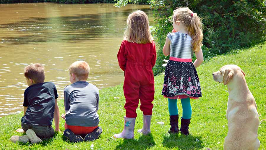 Children stand at the edge of a waterway