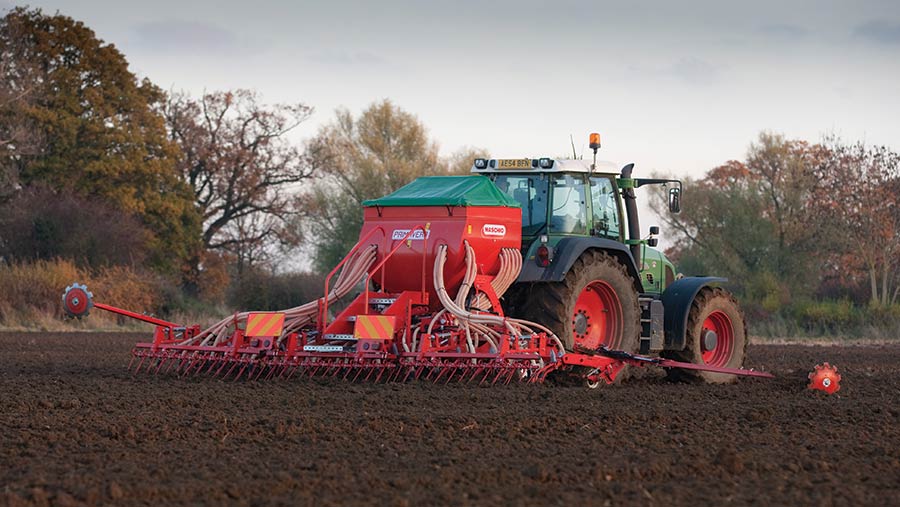 A tractor and seed drill in November, with bare trees