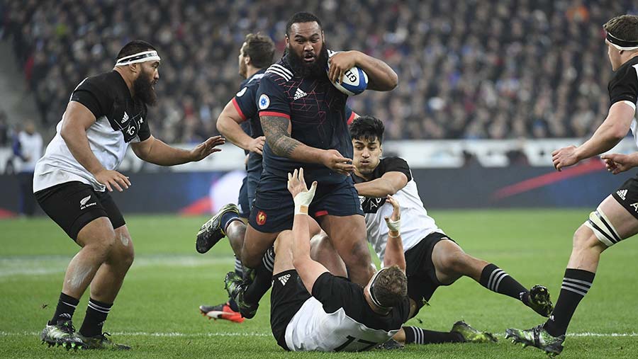 French rugby player Uini Antonio running with the ball while being tackled by two players