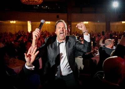 Man celebrating in black tie holding a microphone at the Farmers Weekly Awards